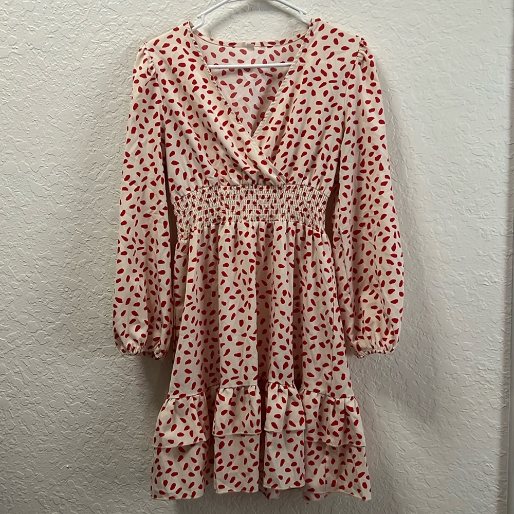 Short length, long sleeve, cream dress with red spots.